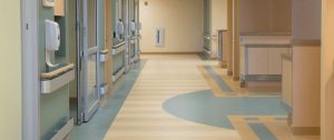 Multi-colored commercial resilient sheet vinyl flooring with custom geometric pattern design in a hospital corridor by All Floors Commercial.